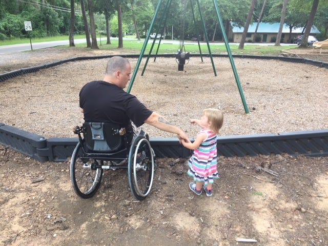 A man in a wheelchair can not access a swing set due to inaccessible terrain.
