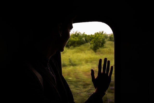 A photo of a man looking outside a train window by Amine rock hoovr on Unsplash.