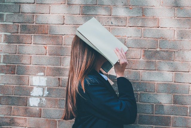 School girl holding book over head