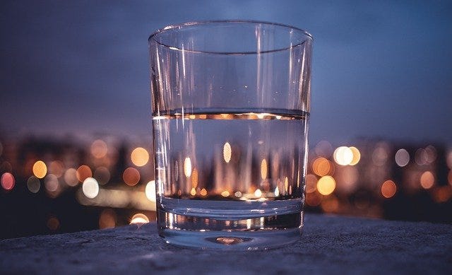A cup of water with a city view on the background