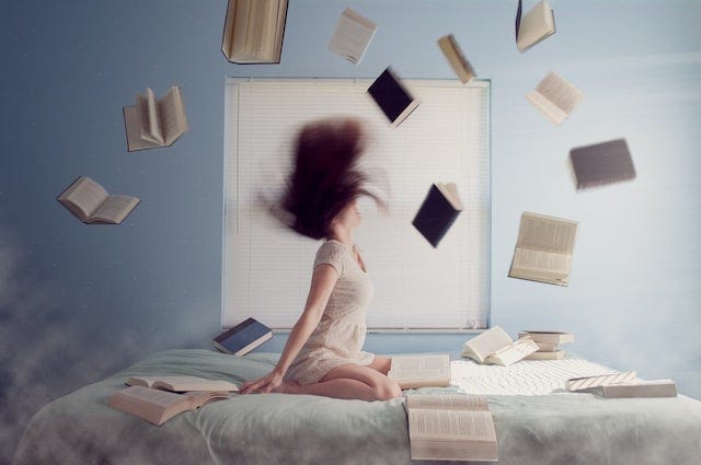 woman sittting on bed with flying book picture