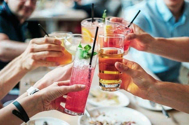 Several hands holding cocktail glasses, making a toast.
