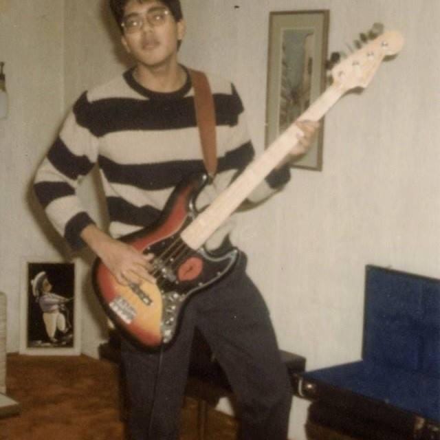 Author is depicted as a teenager enthusiastically playing a Fender Jazz bass guitar with a cherry sunburst finish. He is wearing black pants and a tan sweater with large black stripes.