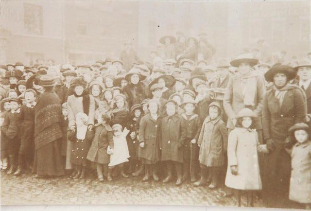 A sepia photo of a crowd of people from the late 19th Century.