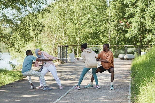 A group of 4 friends playing Tug of War. Two people on each side