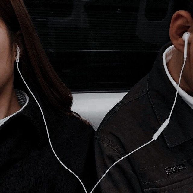 The picture depicts two people sharing earphones on the midnight train.