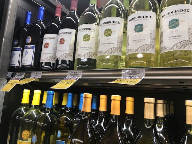 Two shelfs of wine in a grocery store.