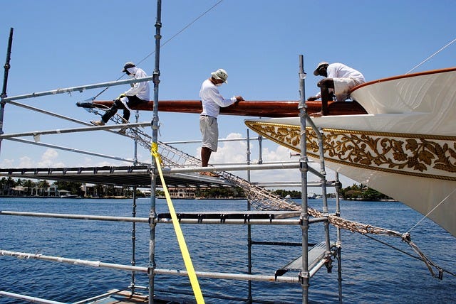 3 guys working at the front of the ship on scaffolding