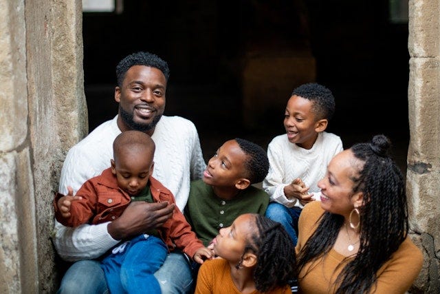 Smiling Black father with four children and smiling partner
