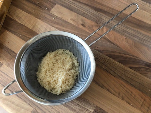 Drain the soaking rice in a sieve and pour over cold water to wash.