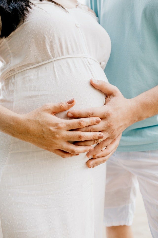 Maternity photo with couples hands on the bump. Photo by Jonathan Borba from Pexels