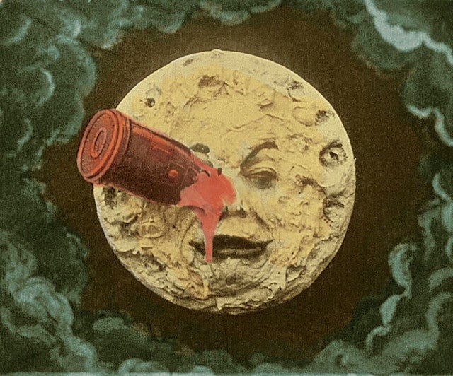 Colourized film still of moon in circle of green clouds with face in frown and red rocket piercing left eye.