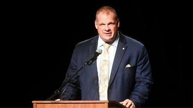 Glenn “Kane” Jacobs behind a podium.