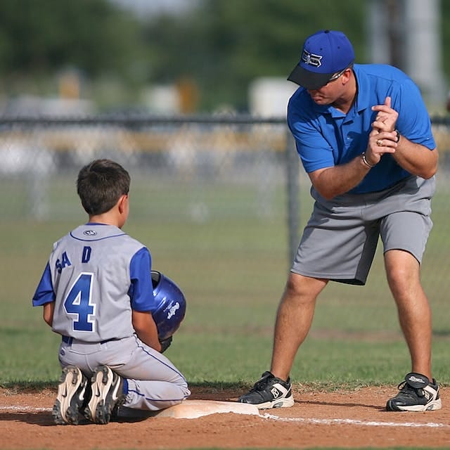 Baseball coach showing a kid how to bat