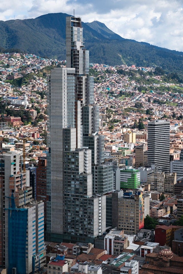 Edificio moderno alto en medio de una ciudad con pocos edificios significativamente más bajos y una gran cantidad de pequeñas casas