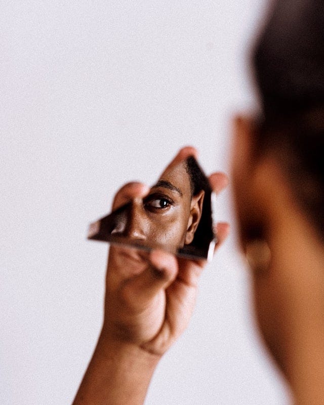 Person looking at self in piece of broken mirror