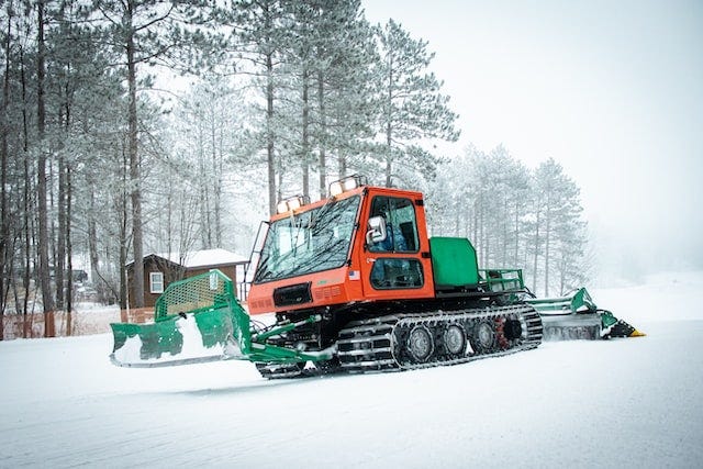 Snow groomer plowing through wintery forest
