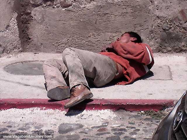 An intoxicated man lies unconscious on the street in the middle of the day