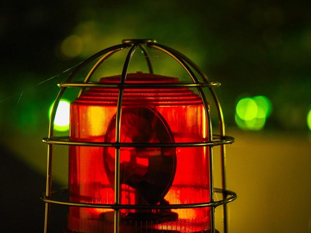 Photo of a red siren atop a vehicle a night.