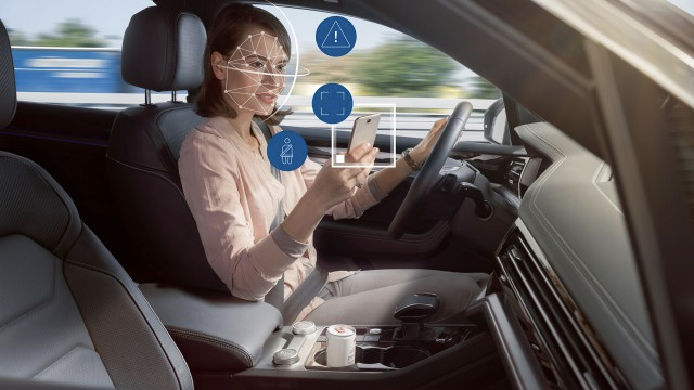 Illustrative photo of a person driving a car while looking at a phone. Lines and icons are superimposed on the photo to show that the car is tracking the attention of the person.