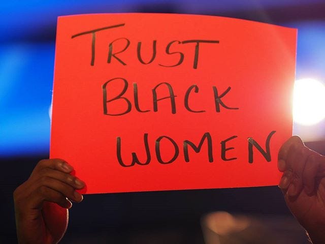 A bright red poster with the phrase: Trust Black Women