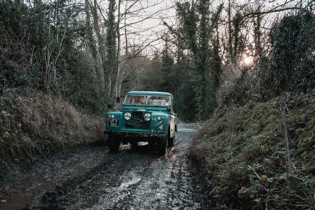 Jeep drives down a muddy road in the forest.