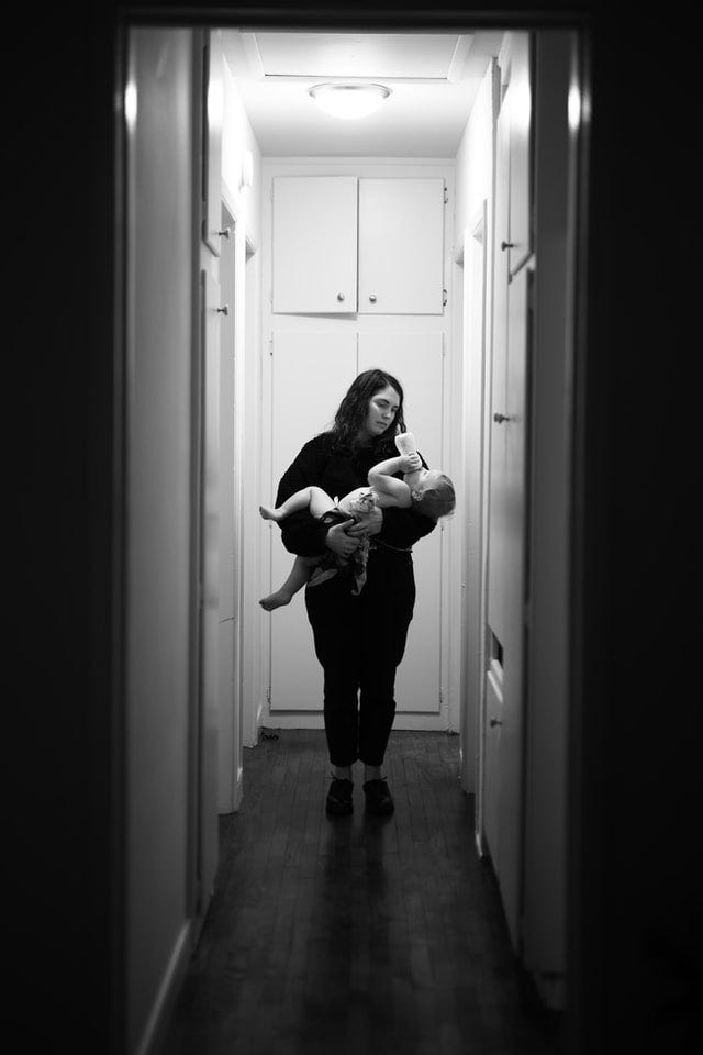 Woman standing in a hallway feeding baby a bottle