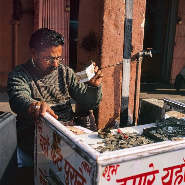 Man in black sweater examining bills and coins.
