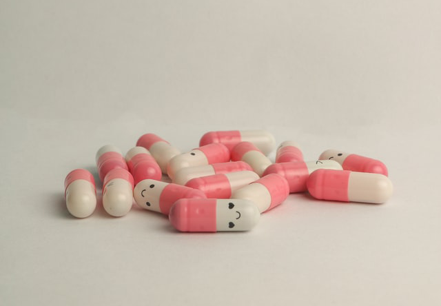 Pink and white pills with smily faces on them, Nyk, Medium