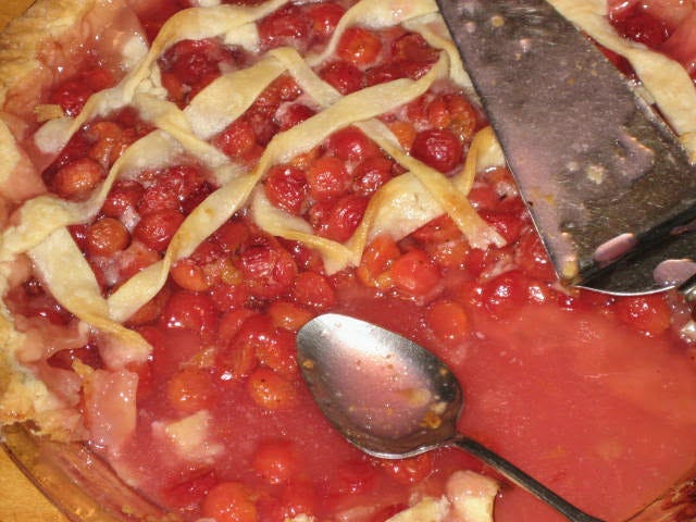 bright red cherry pie, lattice top crust, cut into, with spoon and server