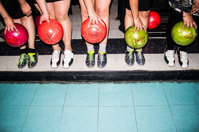 Five people in row holding different bowling balls. (pic from https://unsplash.com/@danielalvasd)