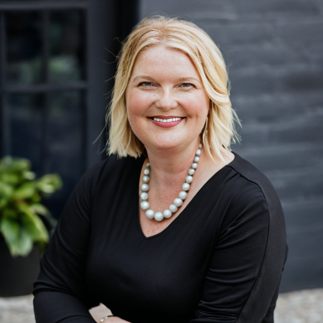 Amy Leneker photo wearing a black blouse and white necklace.