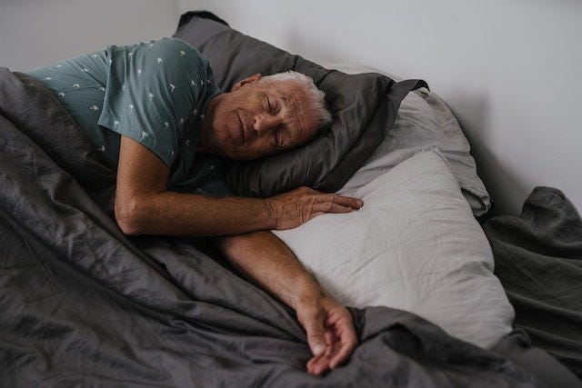 A old man sleeping on his bed