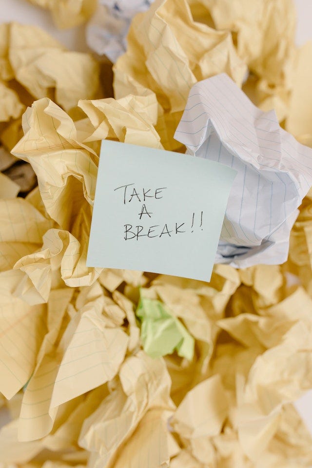 A sticky note that says ‘take a break’ on top of crumbled pieces of yellow paper