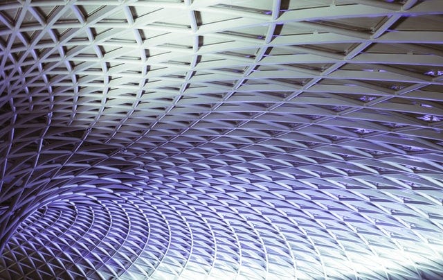 The complex roof structure of Kings Cross train station in London showing an intricate pattern of triangular steel beams.