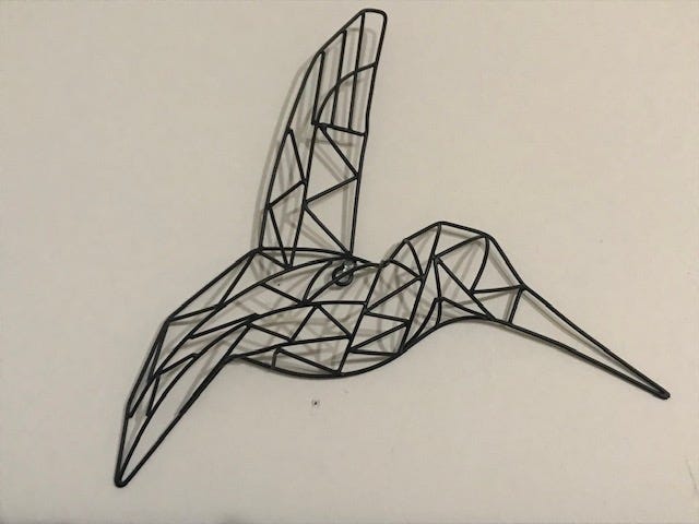 Two-dimensional iron sculpture of a bird hanging on the wall.