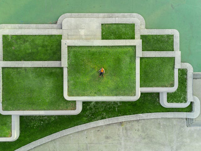 Very high drone view of a man lying on grass.