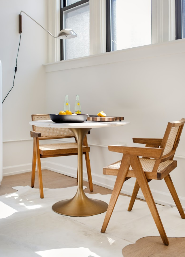 The interior design details of a Bespoke Blueground apartment; two rattan chairs and a brass kitchen table