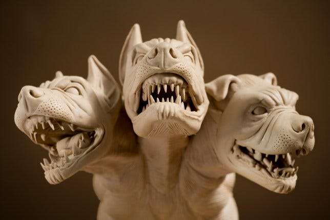 A beige-colored statue of Cerberus, the hound of Hades, via Getty Images and Metro.co.uk. Three dog heads snarl, baring sharp teeth.