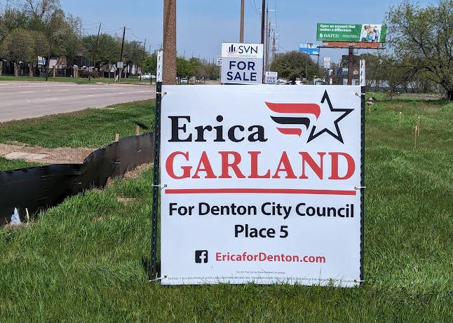 a property “for sale” sign showing above an Erica Garland sign