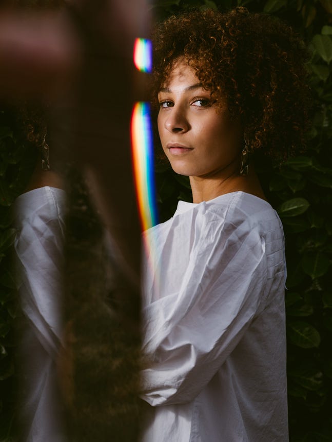 Model in white shirt, with rainbow lens flare in frame