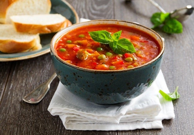 A bowl of minestrone soup with bread.