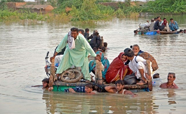 Families trying to wade through floodwater in Pakistan