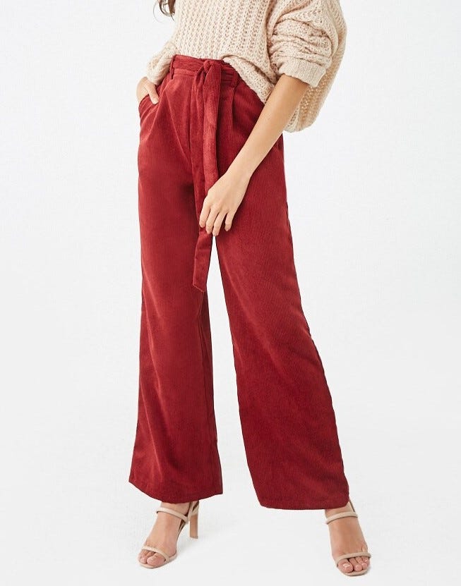 A Forever 21 model wearing burgundy corduroy high-waisted pants with a matching corduroy belt.