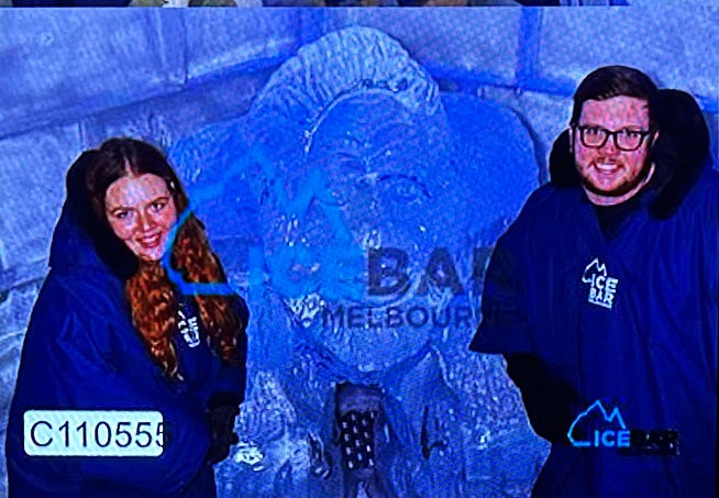 Blurry image of people in ponchos beside a yeti ice sculpture