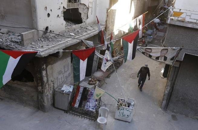 Un hombre camina entre edificios destruidos decorados con banderas palestinas en el campo de refugiados de Yarmuk, al sur de Damasco, el 1 de noviembre de 2018. (Foto: Luai Beshara / AFP)