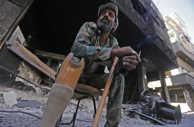 Un hombre palestino herido en una pierna, sentado junto a edificios destruidos del campo de refugiados de Yarmuk, al sur de Damasco, el 1 de noviembre de 2018. (Foto: Luai Beshara / AFP)