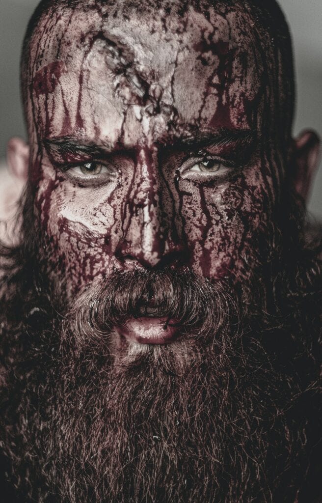 A man with a plush beard with a face covered in the byproducts of battle. Photo courtesy of Shahin Khalaji at Pexels