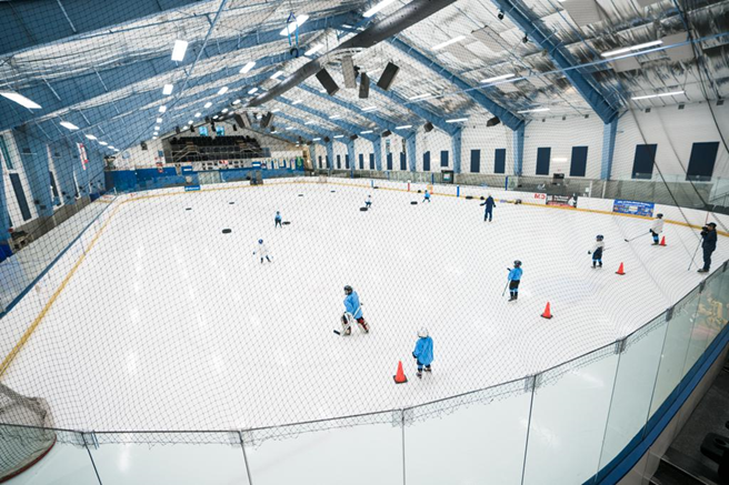 Aerial view of the Palm Beach Ice Works ice rink. Young kids are participating in hockey practice on the ice.