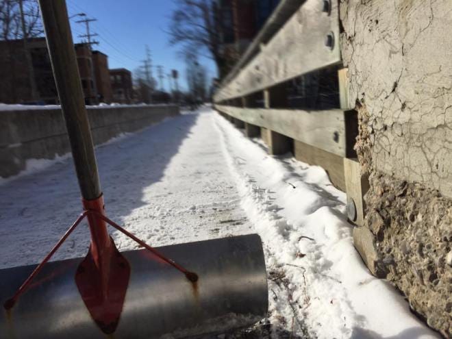 Shovel on snow-covered bridge walkway.